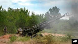FILE - Ukrainian soldiers fire at Russian positions from a U.S.-supplied M777 howitzer in Ukraine's eastern Donetsk region, June 18, 2022. As the anniversary of the Russian invasion of Ukraine nears, some Americans are growing weary of providing support to Ukraine.