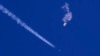 Na fotografiji Čad Fiša, vide se ostaci velikog balona kako padaju ka Atlantskom okeanu, nedaleko od obale Južne Karoline, dok borbeni avion prolazi pored ostavljajući kondenzacijski trag, 4. februara 2023.