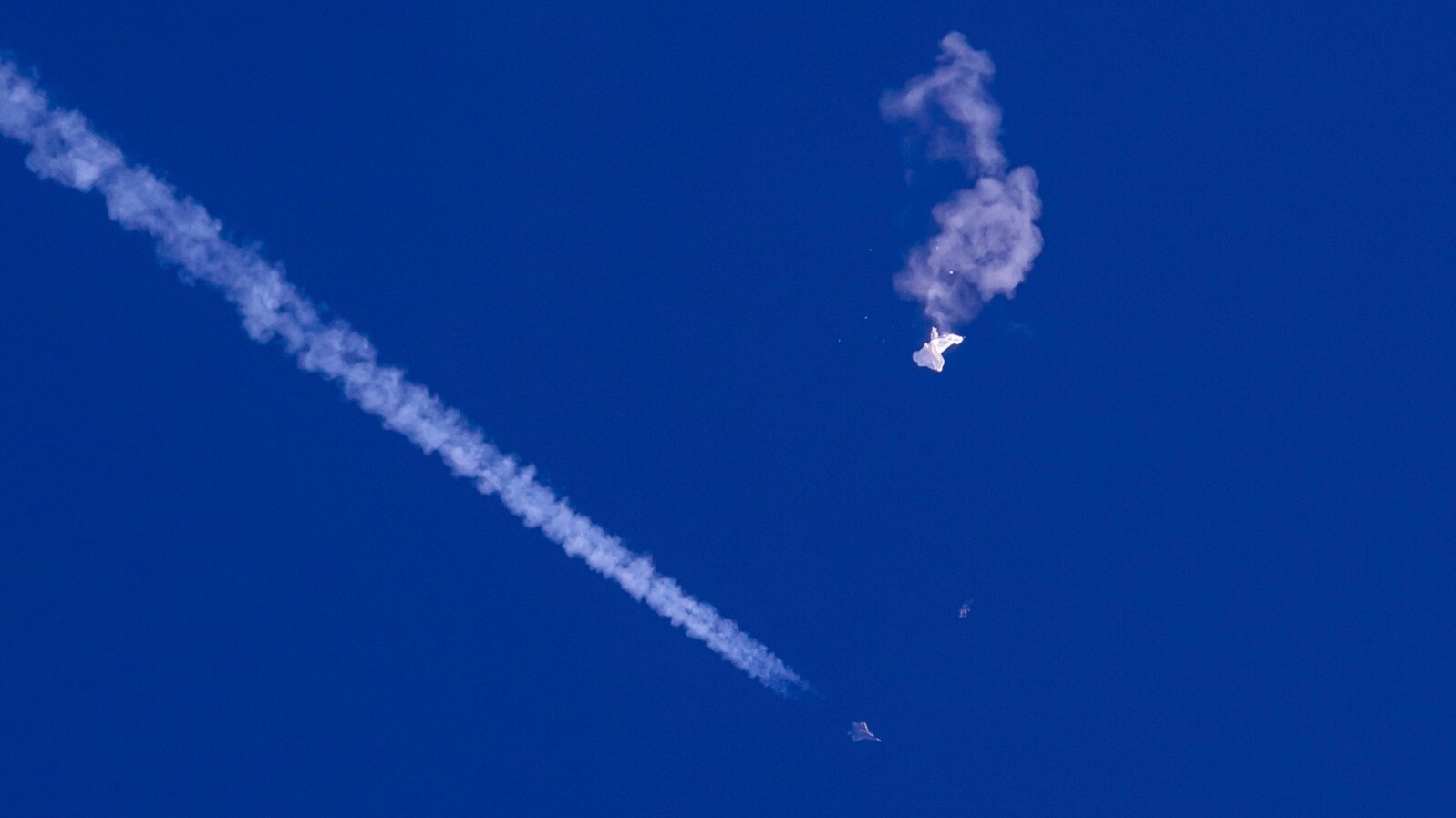 Na fotografiji Čad Fiša, vide se ostaci velikog balona kako padaju ka Atlantskom okeanu, nedaleko od obale Južne Karoline, dok borbeni avion prolazi pored ostavljajući kondenzacijski trag, 4. februara 2023.