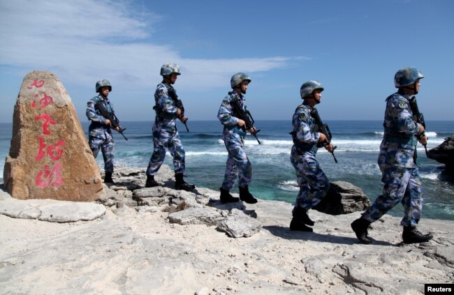 Tentara Angkatan Laut Tentara Pembebasan Rakyat (PLA) China berpatroli di Pulau Woody, di Kepulauan Paracel, yang dikenal di China sebagai Kepulauan Xisha, 29 Januari 2016. Tulisan di batu itu berbunyi, "Naga Tua Xisha". (Stringer/Foto Arsip /REUTERS)