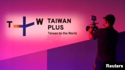 FILE - A staff member takes a video of the logo of TaiwanPlus, a new government-backed English-language online news platform, after the launching ceremony of the platform, in Taipei, Taiwan, Aug. 30, 2021.