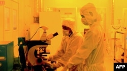 FILE - Researchers wearing bunny suits work inside the semiconductor fabrication lab at the Centre for Nano Science and Engineering (CENSe), situated at the Indian Institute of Science (IISc), in Bangalore on June 30, 2018. 