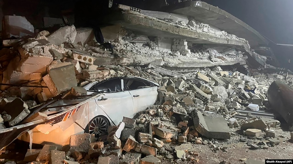 Sebuah mobil terlihat di bawah reruntuhan bangunan yang runtuh, di Kota Azmarin, Suriah utara, Senin, 6 Februari 2023. (Foto: AP)
