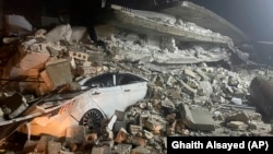 Sebuah mobil terlihat di bawah reruntuhan bangunan yang runtuh, di Kota Azmarin, Suriah utara, Senin, 6 Februari 2023. (Foto: AP)