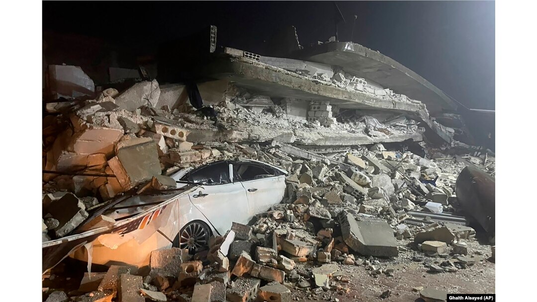 A car is seen under the wreckage of a collapsed building, in Azmarin town, northern Syria, Monday, Feb. 6, 2023. (AP Photo/Ghaith Alsayed)