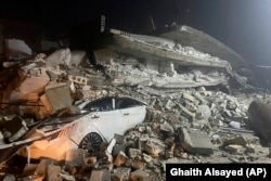 A car is seen under the wreckage of a collapsed building, in Azmarin town, northern Syria, Monday, Feb. 6, 2023. (AP Photo/Ghaith Alsayed)
