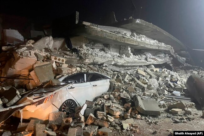 A car is seen under the wreckage of a collapsed building, in Azmarin town, northern Syria, Monday, Feb. 6, 2023. (AP Photo/Ghaith Alsayed)