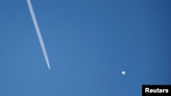 Un avión vuela junto a un presunto globo espía chino mientras flota frente a la costa en Surfside Beach, Carolina del Sur, EEUU, el 4 de febrero de 2023.