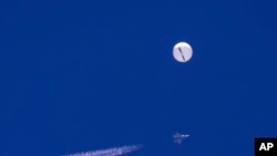 Sebuah balon besar melayang di atas Samudra Atlantik, tepat di lepas pantai South Carolina, sebuah jet tempur dan jejak pesawat terlihat berada di bawahnya, Sabtu, 4 Februari 2023. (Chad Fish via AP)