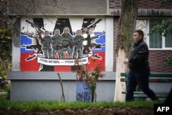 FILE - A pedestrian walks past a mural depicting Russia's paramilitary mercenaries Wagner Group reading "Wagner Group - Russian knights" on a building's wall in Belgrade, on Nov. 17, 2022.