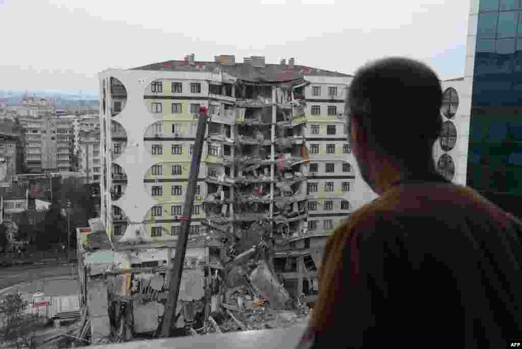 A man looks on at search and rescue operations conducted in the rubble of a collasped building, in Diyarbakir, Turkey, Feb. 6, 2023,