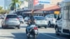Una mujer conduce un scooter por la transitada Calle 8 de la Pequeña Habana, en Miami, el 25 de enero de 2023. Las motos de bajo cubicaje dificultan el ya complicado tráfico en la ciudad, pero muchas veces sirve de salvavidas a migrantes recién llegados, en su mayoría cubanos. 