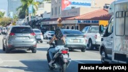 Una mujer conduce un scooter por la transitada Calle 8 de la Pequeña Habana, en Miami, el 25 de enero de 2023. Las motos de bajo cubicaje dificultan el ya complicado tráfico en la ciudad, pero muchas veces sirve de salvavidas a migrantes recién llegados, en su mayoría cubanos. 