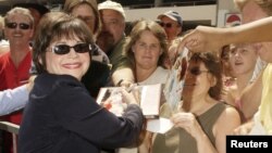 FILE - Cindy Williams, who co-starred with Penny Marshall in the 1970s hit TV series "Laverne & Shirley," signs autographs following ceremony honoring the two with stars on the Hollywood Walk of Fame on Aug. 12, 2004.