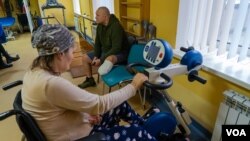 Andriy, 44, sitting in background, says he will return to the front lines when he is able to fully use his prosthetic leg, in Lviv, Ukraine, Jan. 16, 2023. (Yan Boechat/VOA)