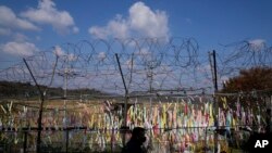 FILE - A visitor walks near the wire fences decorated with ribbons with messages wishing for the reunification of the two Koreas at the Imjingak Pavilion in Paju, South Korea, Oct. 28, 2022. 