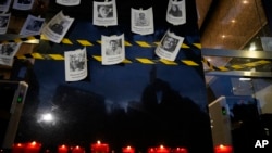 FILE - Photos of slain journalists are displayed on a wall during a vigil to protest the murder of journalist Fredid Roman, outside Mexico's Attorney General's office in Mexico City, Aug. 24, 2022.