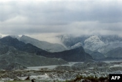 FILE - Heavy rain clouds hang over Mount Pinatubo volcano, still emitting steam and ash clouds as a lake of trapped volcanic debris lies on its slope, on June 29, 1991.