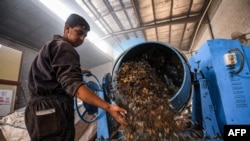 A worker dumps plastic out of a mixer before it is recycled into tiles at the startup known as TileGreen, based near Egypt's capital, on Dec. 8, 2022.