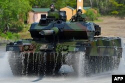 FILE - This photo taken May 20, 2019, shows soldiers on a Leopard 2 A7 main battle tank of the German armed forces Bundeswehr driving at a military training area in Munster, northern Germany.