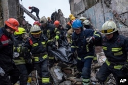 Rescue workers carry the body of a man who was killed in a Russian missile strike on an apartment building in the southeastern city of Dnipro, Ukraine, Jan. 16, 2023.