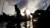 FILE - Fishermen are silhouetted as they arrive their wooden boats at the river bank after they collect fish on the Mekong River during the fish-harvesting season near Phnom Penh, Cambodia, Nov. 28, 2018. 