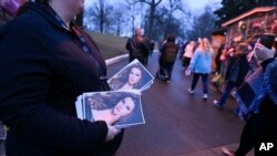 An attendant holds programs as fans enter Graceland for a memorial service for Lisa Marie Presley, Jan. 22, 2023, in Memphis, Tenn. 