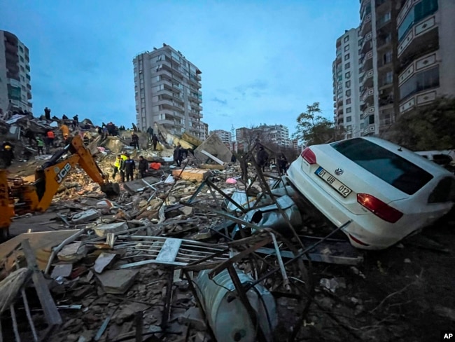 Tim darurat mencari korban di antara puing-puing gedung yang hancur di Adana, Turki, 6 Februari 2023. (Foto: via AP)