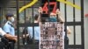 FILE - A protester stands behind a mock jail bars with photos of 47 imprisoned pro-democracy figures to be tried under a new national security law, in Hong Kong, Sept. 19, 2021. Their trial is going underway Monday.