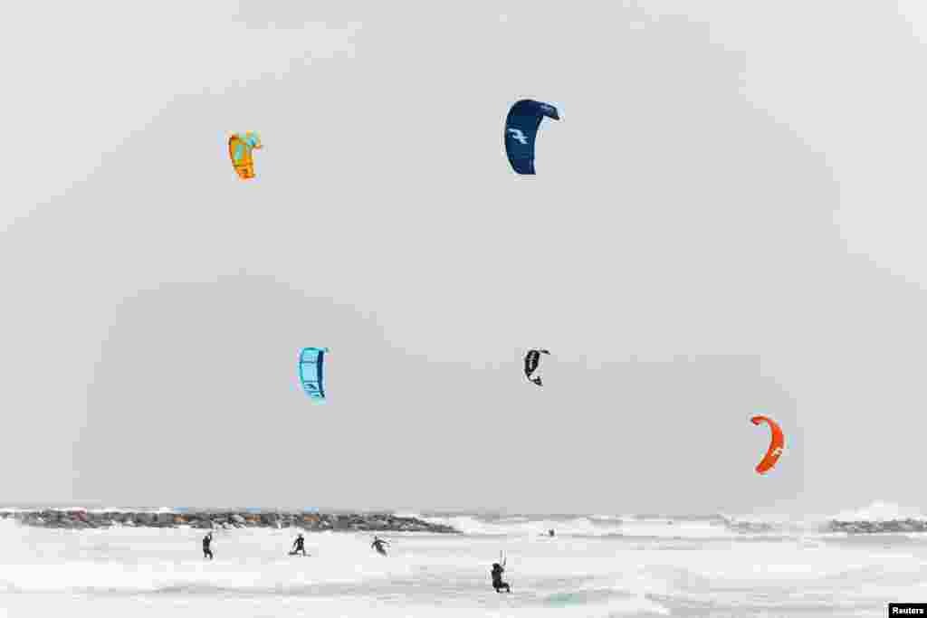 Israelis surf with their kitesurfing boards in the Mediterranean sea during a stormy weather in Ashkelon, Feb. 1, 2023.