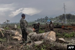 Ezekiya Yadi Jackson (L), 20, refuels his chainsaw at the foot of Nyiragongo Volcano in Virunga National Park, Democratic Republic of Congo, Jan. 13, 2023.