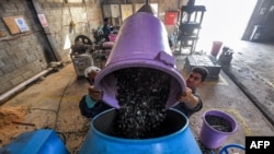 Los trabajadores vierten desechos plásticos en un mezclador antes de que se reciclen en baldosas en la empresa emergente conocida como TileGreen, con sede cerca de la capital de Egipto, el 8 de diciembre de 2022.