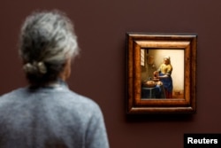 A man looks at Vermeer's painting 'The Milkmaid' at an exhibition bringing together 28 works by Dutch painter Johannes Vermeer at the Rijksmusuem in Amsterdam, Netherlands February 6, 2023. (REUTERS/Piroschka van de Wouw)