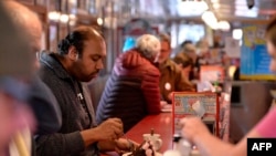 FILE - A customer sits at the counter at the Red Arrow Diner in Manchester, N.H., Feb. 8, 2020. Every four years, presidential hopefuls' visits to New Hampshire give a welcome economic boost to local businesses turned into political pit stops.