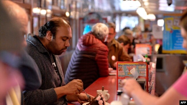 FILE - A customer sits at the counter at the Red Arrow Diner in Manchester, N.H., Feb. 8, 2020. Every four years, presidential hopefuls' visits to New Hampshire give a welcome economic boost to local businesses turned into political pit stops.