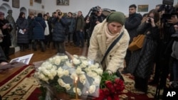 La gente deposita flores en honor a los voluntarios extranjeros Chris Parry y Andrew Bagshaw, asesinados en el este de Ucrania golpeado por la guerra, durante un servicio conmemorativo en la Catedral de Santa Sofía en Kiev, Ucrania, el 29 de enero de 2023.