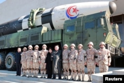 Pemimpin Korea Utara Kim Jong Un dan putrinya menghadiri sesi foto dengan para ilmuwan, insinyur, dan lainnya yang terlibat dalam uji coba ICBM Hwasong-17 baru dalam foto yang dirilis 27 November 2022 ini. (Foto: via Reuters)