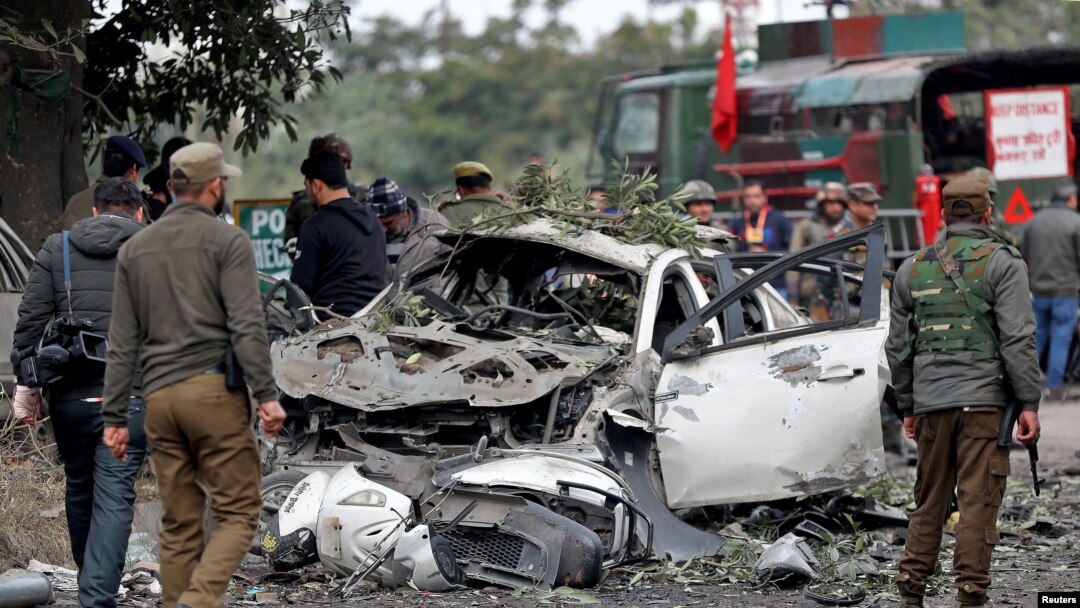 Indian security force personnel stand guard next to a damaged vehicle after a bomb blast in Narwal area of Jammu, Jan. 21, 2023. 