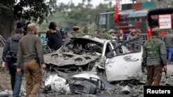 Indian security force personnel stand guard next to a damaged vehicle after a bomb blast in Narwal area of Jammu, Jan. 21, 2023. 