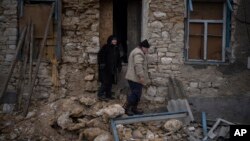 Oleksandra Hryhoryna, left, inspects her house which was damaged by shelling last fall, in Kalynivske, Ukraine, Jan. 28, 2023. 