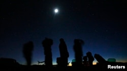 FILE - The moon shines above a group of people on the lookout for unidentified flying objects tour in the desert outside Sedona, Arizona, Feb. 14, 2013. NASA said Sept. 14, 2023, it has selected a research director to investigate UFO sightings.