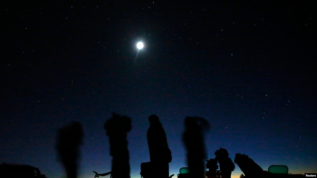 Bulan purnama bersinar di atas sekelompok orang yang sedang memburu UFO di padang pasir di luar Sedona, Arizona, 14 Februari 2013. (Foto: Mike Blake/Reuters)
