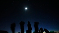 Bulan purnama bersinar di atas sekelompok orang yang sedang memburu UFO di padang pasir di luar Sedona, Arizona, 14 Februari 2013. (Foto: Mike Blake/Reuters)