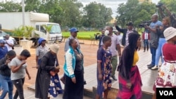 Journalists, in background, are seen outside Harare Magistrate Courts, in Harare, Zimbabwe, Jan. 16, 2023, before being turned away by police. (Columbus Mavhunga/VOA)