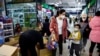 FILE - A woman and a child walk past workers sorting toys at a shopping mall in Beijing, Jan. 11, 2023. 