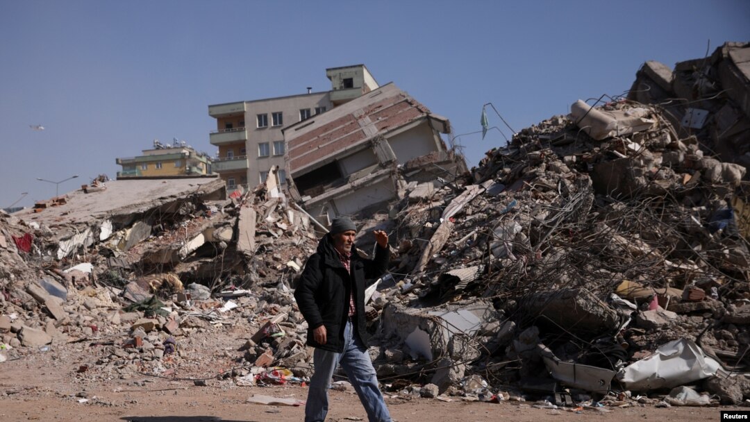 A man walks past rubble at the site of a collapsed building, in the aftermath of a deadly earthquake in Kahramanmaras, Turkey, Feb. 12, 2023. 