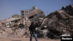 A man walks past rubble at the site of a collapsed building, in the aftermath of a deadly earthquake in Kahramanmaras, Turkey, Feb. 12, 2023. 