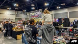 Para pengunjung, termasuk di antaranya anak kecil, melihat-melihat senjata api yang dijual di pameran senjata Crossroads of the West Gun Show di Ontario, California, pada 28 Januari 2023. (Foto: AFP/Apu Gomes)