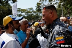 Un miembro de la Policía Nacional Bolivariana habla con trabajadores públicos durante una protesta que exige mejores salarios en medio de la inflación , en Caracas, Venezuela, el 16 de enero de 2023.