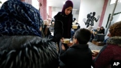 FILE: A volunteer distributes meals following a devastating earthquake, in Latakia, Syria, Feb. 10, 2023. The  7.8 magnitude quake that hit Turkey and Syria has displaced millions in war-torn Syria.